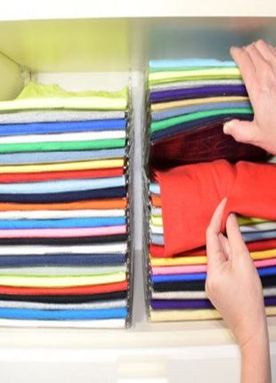 Colorful folded shirts in a cabinet with hands reaching in to organize them.