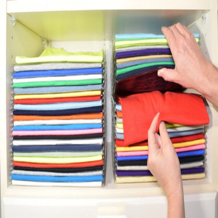 Colorful folded shirts in a cabinet with hands reaching in to organize them.