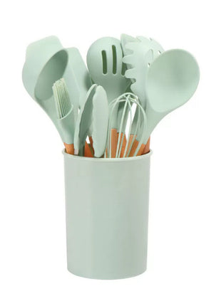 Set of kitchen utensils in a light green holder on a white background