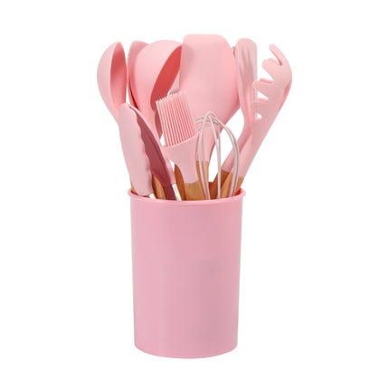 Set of pink kitchen utensils in a pink holder on a white background