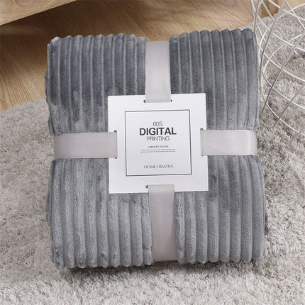 Folded gray textured blanket with a label on a light wooden floor.