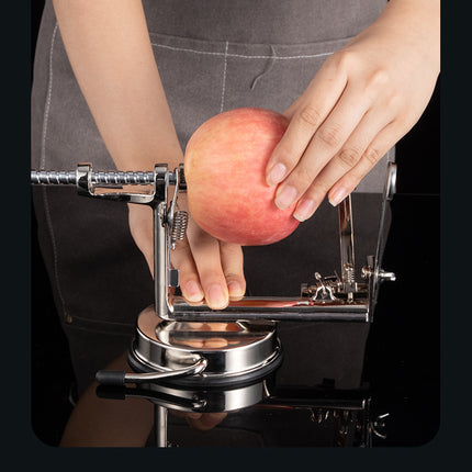 Person using an apple peeler with a red apple on a black background