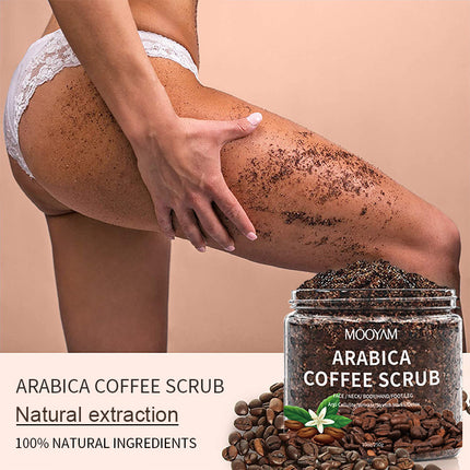 Person using Arabica Coffee Scrub on leg with product jar and coffee beans displayed.