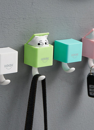 Four colorful wall hooks with cartoon designs on a gray wall.