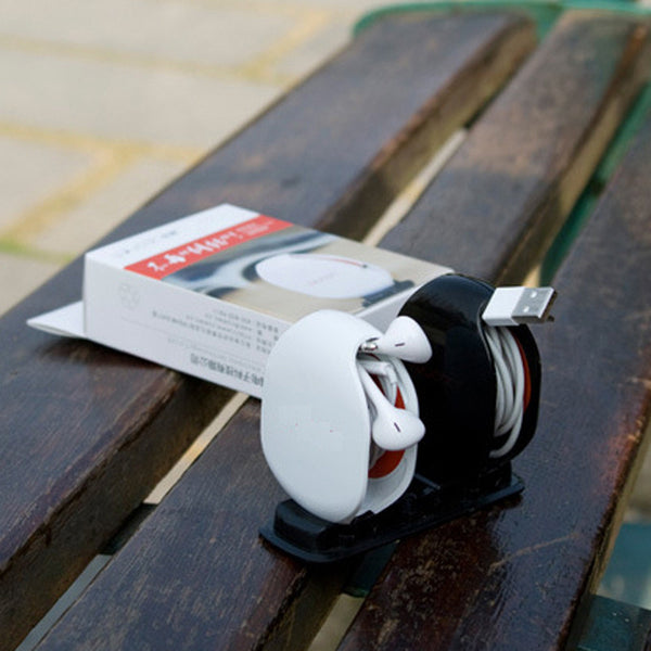 White and black electronic device on a wooden surface with a box in the background
