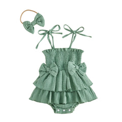 Green baby romper with ruffles and bows, accompanied by a matching headband on a white background.