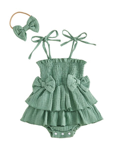 Green baby romper with ruffles and bows, accompanied by a matching headband on a white background.