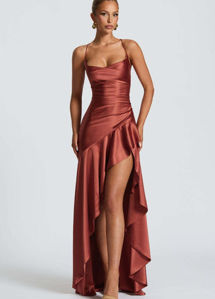 Woman wearing a rust-colored evening gown with a high slit on a white background