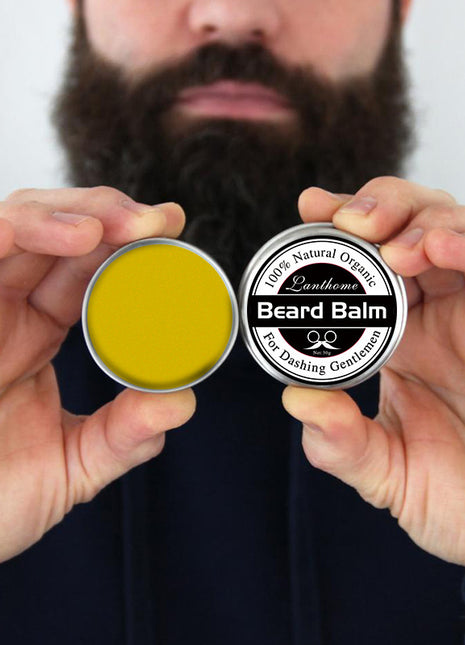 Two containers of beard balm held by hands with a blurred background