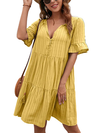 Woman wearing a yellow dress standing in front of green foliage.