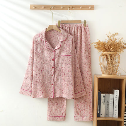 Pink pajama set hanging on a wooden hanger against a white wall with a bookshelf in the background.