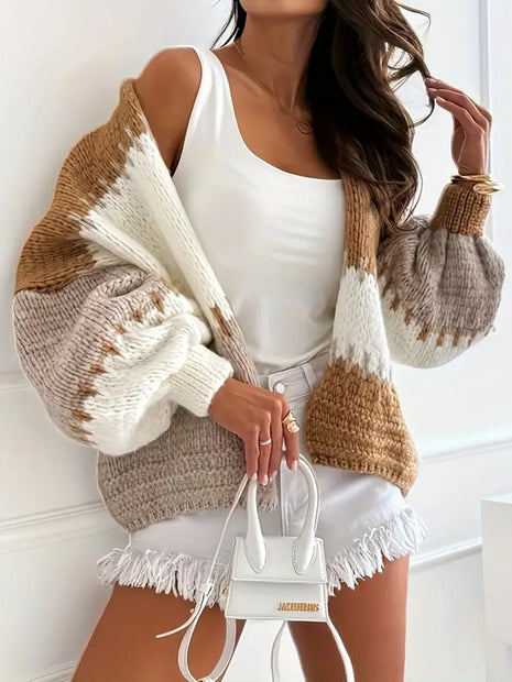 Woman wearing a brown and beige sweater with white accents, holding a white handbag.