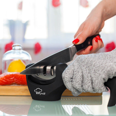 Person using a knife sharpener with a blurred kitchen background