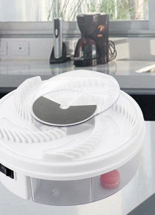 White electronic device on a kitchen counter with a coffee maker and clock in the background