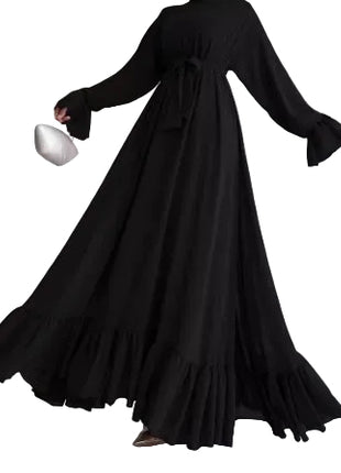 Person wearing a long black dress against a neutral background