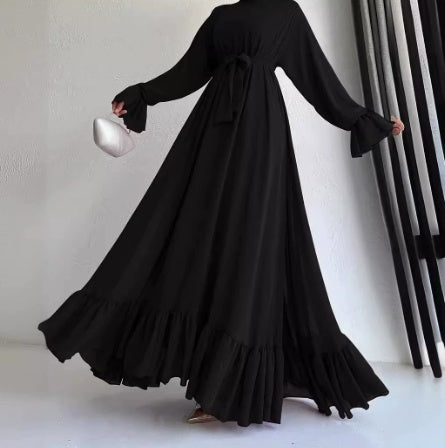 Person wearing a long black dress against a neutral background