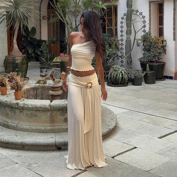 Woman in a white dress standing in a courtyard with plants and a fountain.