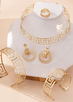 Gold jewelry set including bracelet, ring, and earrings on a white stand with a beige background