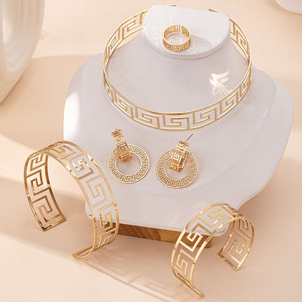 Gold jewelry set including bracelet, ring, and earrings on a white stand with a beige background