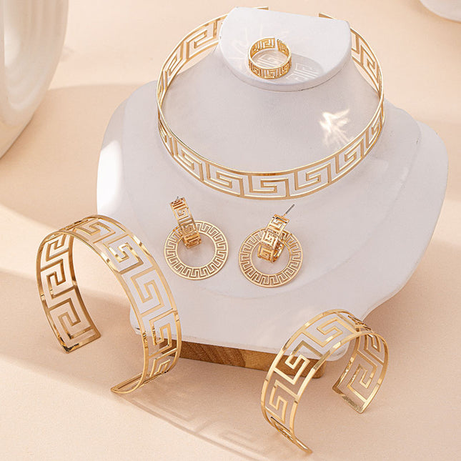 Gold jewelry set including bracelet, ring, and earrings on a white stand with a beige background