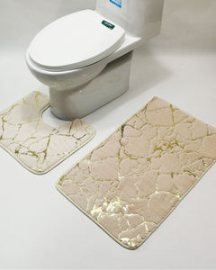 Beige marble-patterned bath mats in front of a white toilet on a light gray background