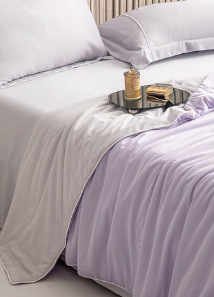 Neatly made bed with light purple bedding and a tray with items on a nightstand.