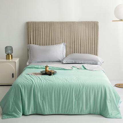 Bed with mint green comforter and beige headboard in a bedroom setting.