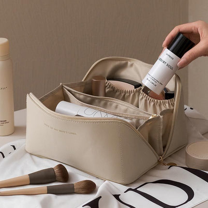 Beige cosmetic bag with makeup items on a white surface