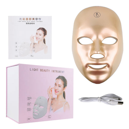 Gold light beauty instrument with packaging and user manual on a white background