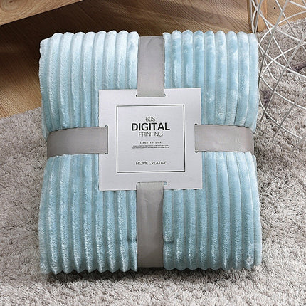 Light blue textured blanket with a brand label on a gray surface