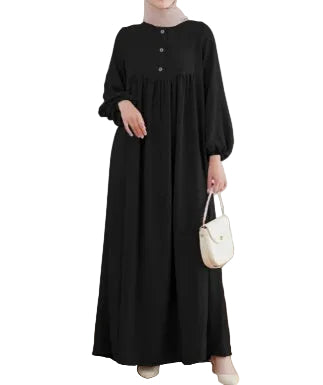 Person wearing a black dress holding a white handbag in a minimalistic room.