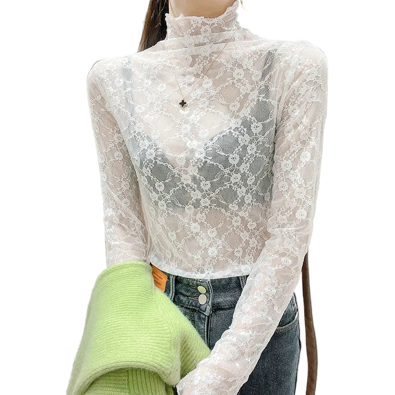 Person wearing a sheer lace long-sleeve top over a green sweater with a neutral background