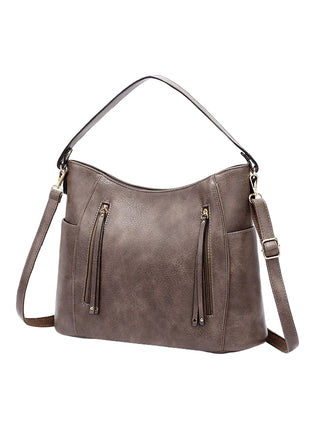 Brown leather handbag with multiple zippers on a white background