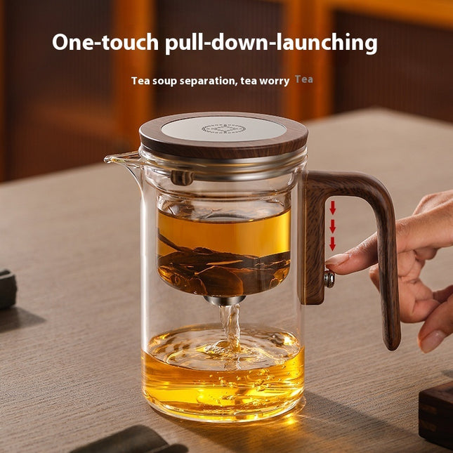 Glass teapot with wooden handle and lid on a table, featuring tea soup separation mechanism.