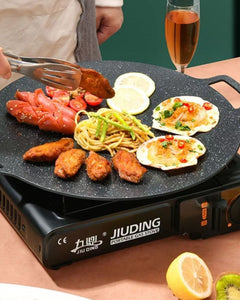 Portable gas stove with food being cooked on a table, featuring the brand 'JIUDING'.