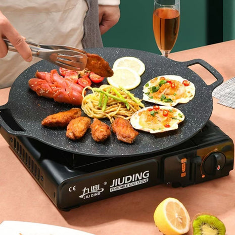 Portable gas stove with food being cooked on a table, featuring the brand 'JIUDING'.