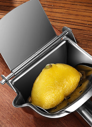 Metal lemon squeezer with a lemon inside on a wooden surface
