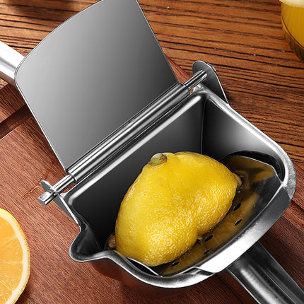 Metal lemon squeezer with a lemon inside on a wooden surface