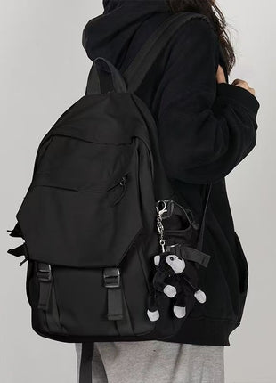 Person wearing a black backpack with a plain background