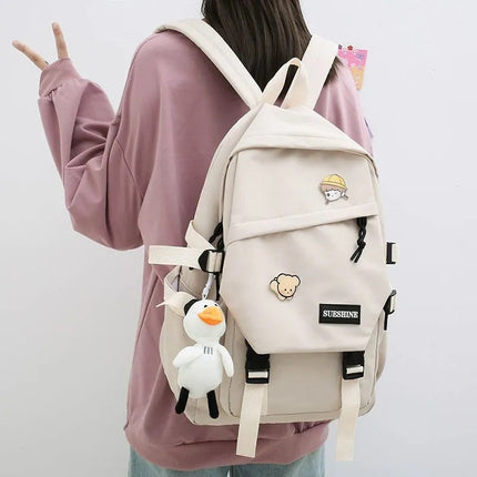 Person wearing a beige backpack with cartoon character decorations on a plain background