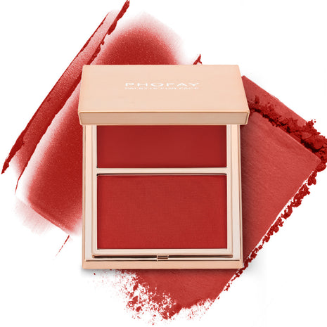 A selection of PHOFAY Duo Cream & Powder Blush products displayed on a pink surface, with the words 'JUST ENOUGH' visible in the image. The products come in golden-colored compact cases with brushes on one side and pink and red blush shades on the other.