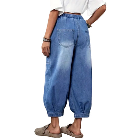 Person wearing blue jeans and a white shirt in a room with a rug and plant.