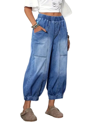 Person wearing blue denim wide-leg pants in a room with a door and plant in the background.
