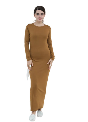 Woman wearing a brown dress standing in a minimalistic room with a vase and chair.