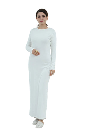 Woman in a white dress standing next to a white chair and potted plant on a light gray background