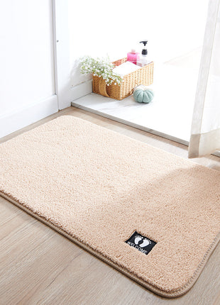 Beige rug with a brand logo on a wooden floor in a room with a window and basket.