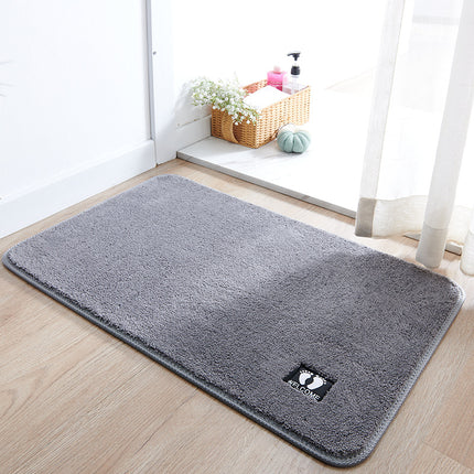Gray doormat with a brand logo on a wooden floor in a bright room.