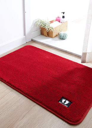 Red doormat with a 'Welcome' label on a wooden floor.