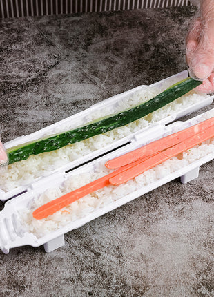 Sushi-making process with a sushi roller and ingredients on a gray surface.