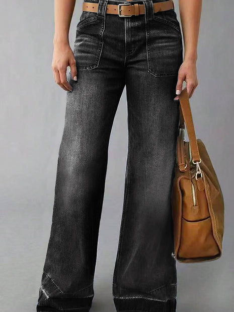 Person wearing black wide-leg jeans holding a brown leather bag on a gray background blndl